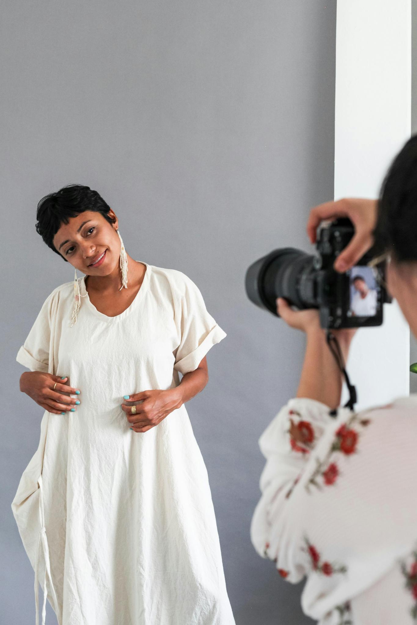 A woman in a white dress being photographed in a studio setting.